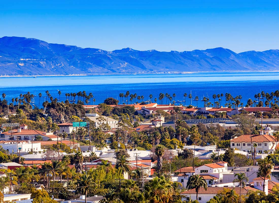 Santa Barbara, CA - Aerial View of Buildings and Homes in Santa Barbara California Surrounded by Palm Trees with Mountains in the Distance