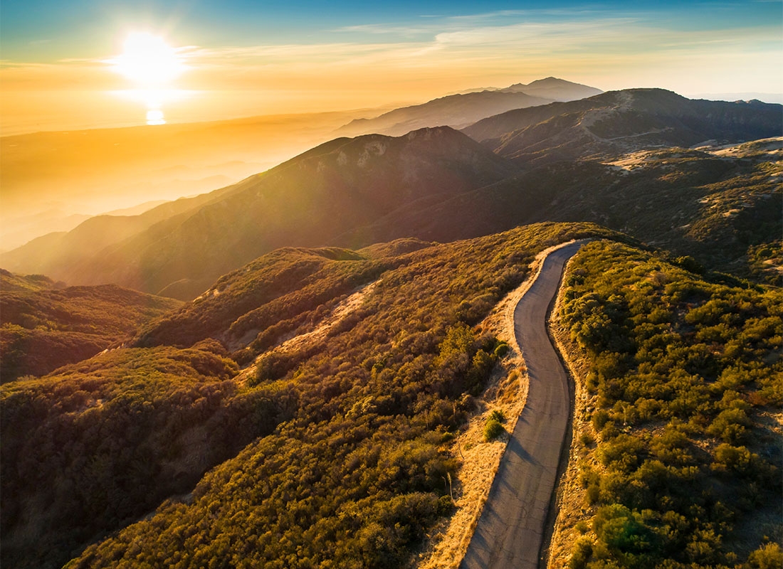 We Are Independent - Aerial View of an Empty Country Road Through the Mountains with a Colorful Sunset Sky in Santa Barbara California