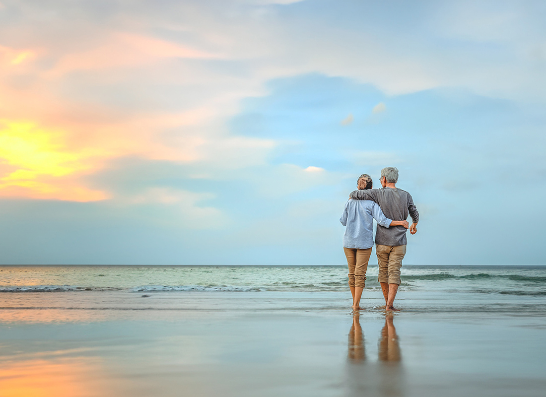 Personal Insurance - Older Couple Standing on Beach at Sunset on a Beautiful Day
